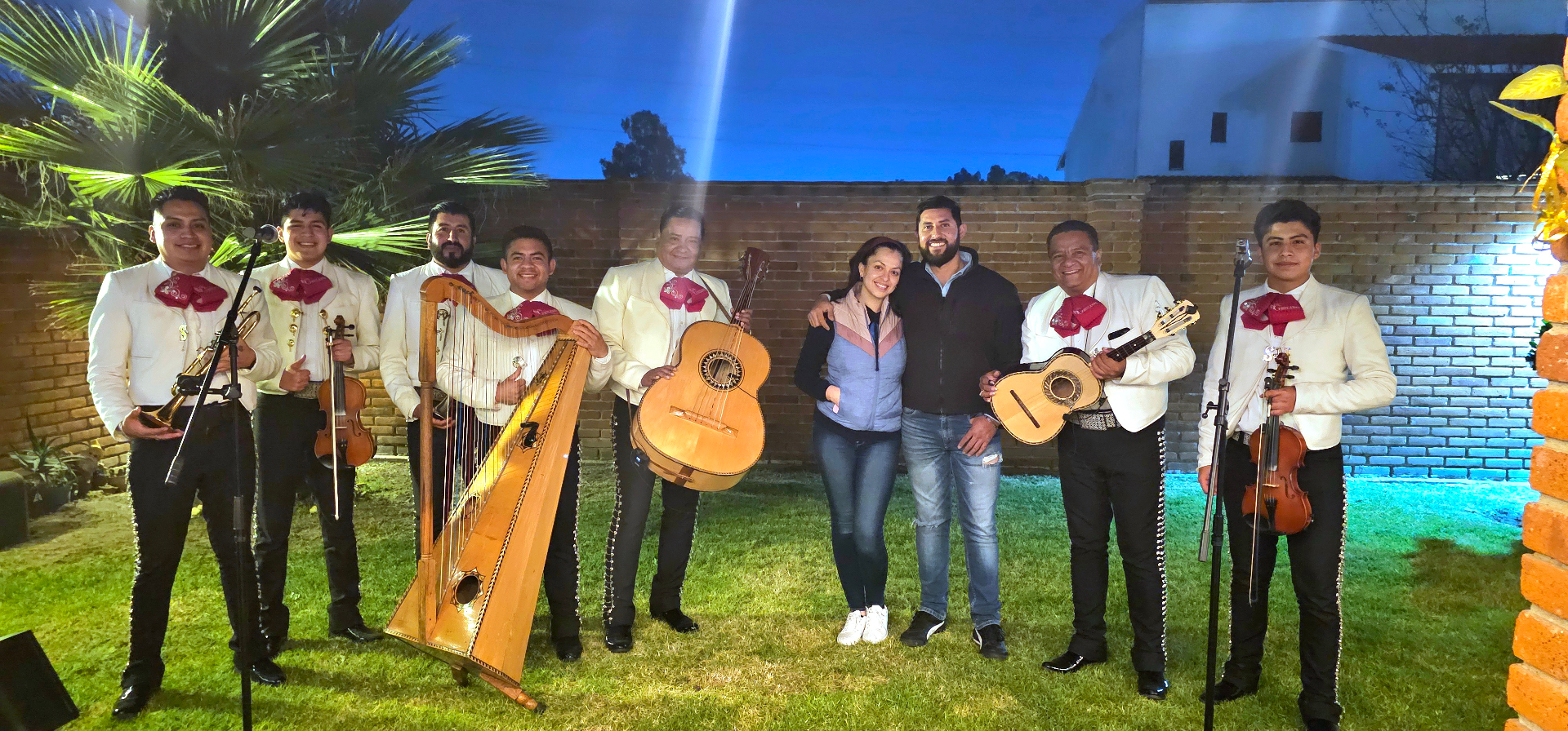 Mariachi posando con clientes en jardín