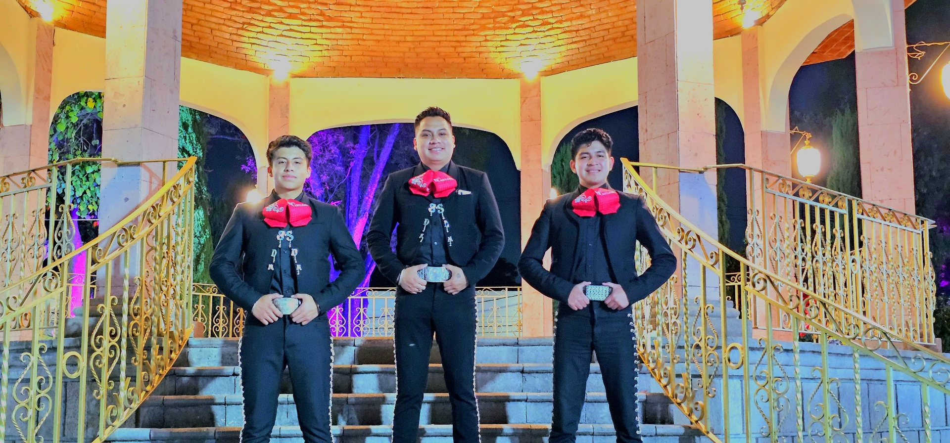 Trío del mariachi posando en kiosco iluminado de noche